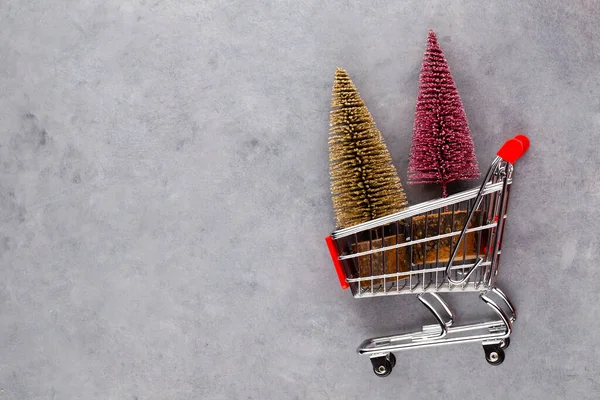 赤いテーブルの上にクリスマスツリーとショッピングカート — ストック写真
