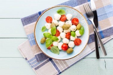 Kiraz domatesleri, mozzarella peyniri, fesleğen ve baharatlar gri tahta üzerinde. İtalyan geleneksel Caprese salata malzemeleri. Akdeniz yemekleri. 