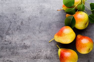 Tabağında yapraklar olan taze bir armut. Gri taş masa.