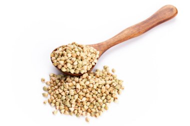 Beyaz arka planda çiğ karabuğday ve tahta kaşık.