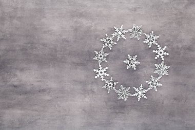 Noel kompozisyonu. Beyaz kar taneleri gri arka plandaki çelenkleri süslüyor. Noel, kış, yeni yıl konsepti. Düz konum, üst görünüm, kopyala.