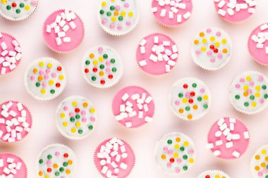 Beyaz arka planda çok renkli, güzel dekore edilmiş muffinler..