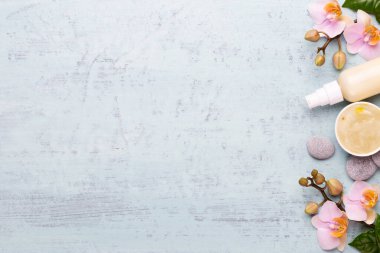 Spa aromaterapi arka planı, basit orkide çiçekleriyle süslenmiş çeşitli güzellik ürünleri..
