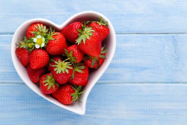 Çilekli kalp. Beyaz ahşap masadaki taze çilekler. Üst görünüm, alanı kopyala. 