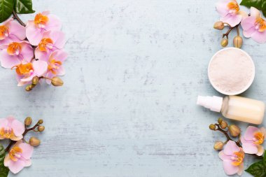 Spa aromaterapi arka planı, basit orkide çiçekleriyle süslenmiş çeşitli güzellik ürünleri..