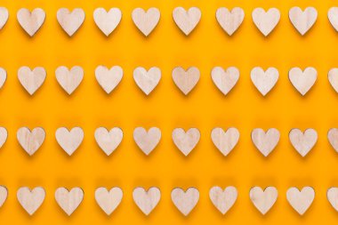 Sarı arka planda küçük tahta kalpler. Yaratıcı bir fikir. Sevgililer Günü tebrik kartı.