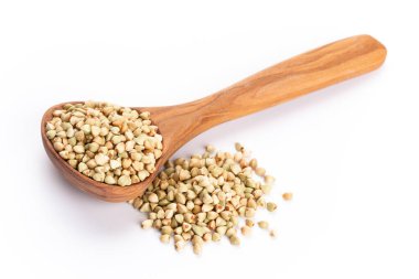 Beyaz arka planda çiğ karabuğday ve tahta kaşık.