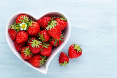 Çilekli kalp. Beyaz ahşap masadaki taze çilekler. Üst görünüm, alanı kopyala. 