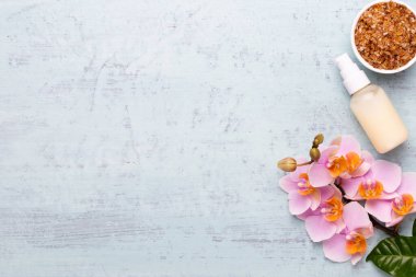 Spa aromaterapi arka planı, basit orkide çiçekleriyle süslenmiş çeşitli güzellik ürünleri..