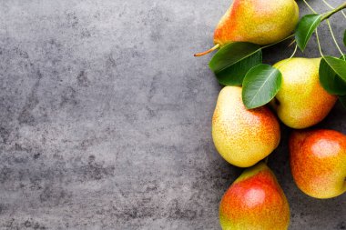 Tabağında yapraklar olan taze bir armut. Gri taş masa.