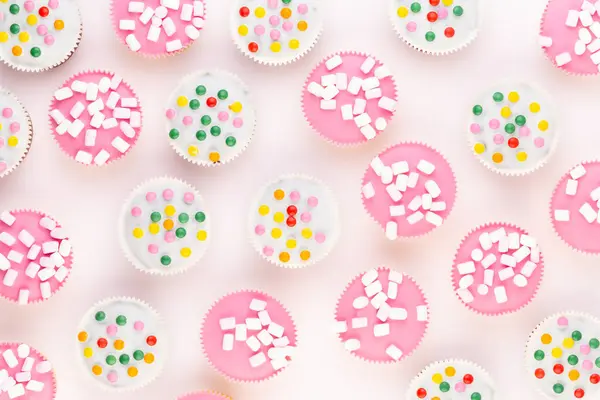 stock image Multiple colorful nicely decorated muffins on a white background, top view.