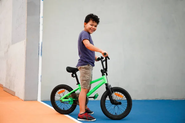 Bisikletiyle parkta dikilen 8 yaşında bir çocuk.