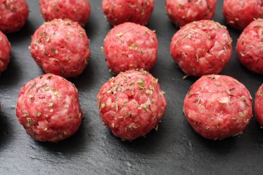 Koyu bazalt tabaktaki parlak ham köfteler.