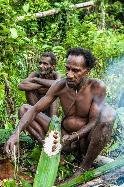 Korowai adam pişmiş sago öneriyor solucanlar