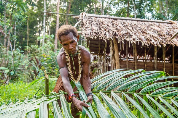 Donna della tribù dei Korowai tesse un cesto di foglie per la pesca — Foto Stock