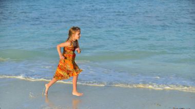 Sevimli küçük kız sahilde günbatımı ışık çalışan. Küba.