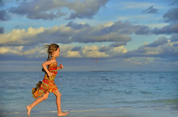 可爱的小女孩在日落的阳光下奔跑在海滩上 — 图库照片