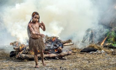 Baliem Vadisi, Batı Papua, Endonezya, 16 Mayıs 2016: Dugum Dani kabile. Kimliği belirsiz çocuk Dugum Dani kabilesinin duman yangında yakındır. 16, Mayıs 2016 yılında Batı Papua, Endonezya.