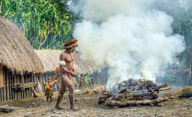 Baliem Vadisi, Batı Papua, Endonezya, 4 Haziran 2016: Dugum Dani kabile köyü. Adam Dugum Dani kabilesinin aşçılar yemek, domuz yemek bir earthoven yöntemini kullanır. Batı Papua. Yeni Gine Adası