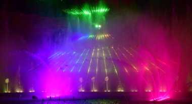 Renkli çeşmeler. Güzel bir lazer ve çeşme gösterisi. Büyük renkli dekoratif dans jeti geceleri hafif fıskiye gösterisine öncülük etti. Koyu