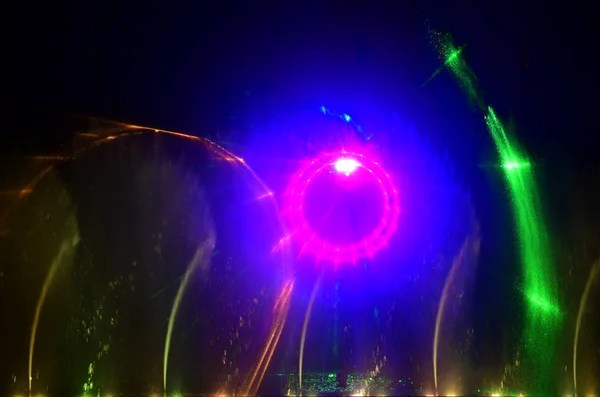 Colorful water fountains. Beautiful laser and fountains show. Large multi colored decorative dancing water jet led light fountain show at night. Dark