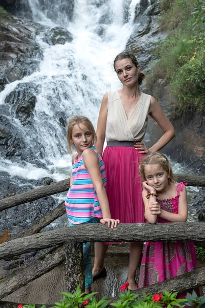 滝で小さな娘と母親の肖像画 幸せな母親と彼女の娘は夏の日に森の中の滝の近くの自然を楽しむ — ストック写真