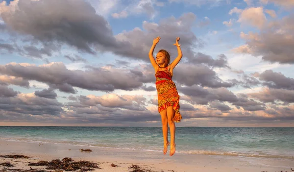 可爱的小女孩在夕阳西下跳到沙滩上 卡亚可可 — 图库照片