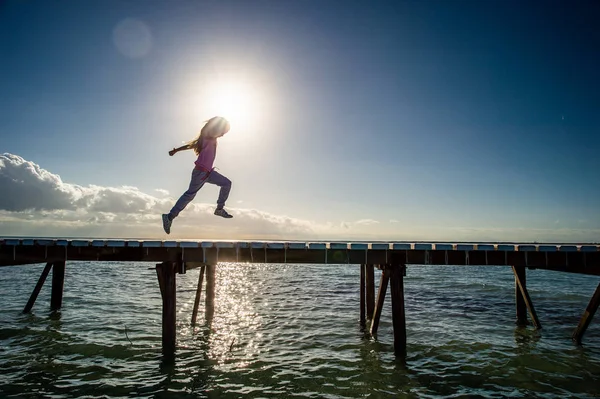 Sylwetka Dziewczynki Biegającej Drewnianym Molo Wschodzie Słońca Słońce Tle Czyste — Zdjęcie stockowe