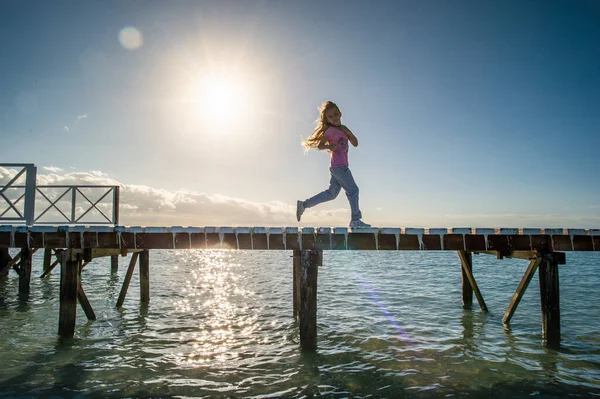 Silhouette Eines Kleinen Mädchens Das Bei Sonnenaufgang Auf Einem Holzsteg — Stockfoto