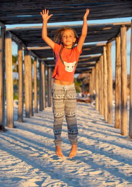 Gün batımında sahilde zıplayan küçük bir kız. Sandy Sahili. Cayo Coco. Küba