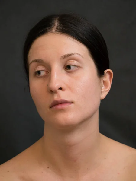 Portrait of Young Woman With Dark Hair Against Dark Background