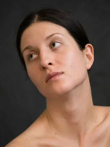 Portrait of Young Woman With Dark Hair Against Dark Background