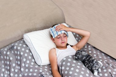 Girl with heatstroke lying in bed. clipart