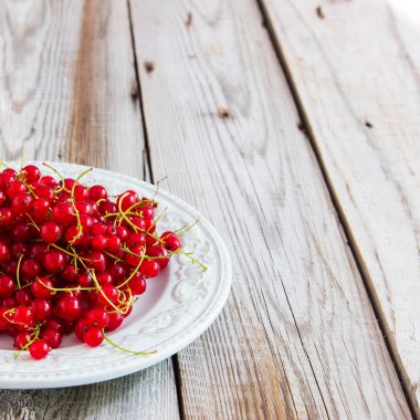 Gri ahşap arka plan üzerinde kırmızı kuş üzümü.