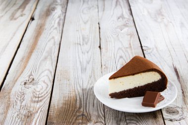 Çikolata-süzme peynir pasta ve ahşap arka plan üzerinde süt.