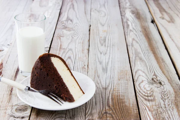 Chocolate-cottage cheese cake and milk on wooden background. — Stock Photo, Image