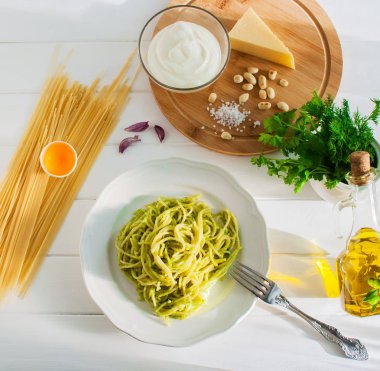 Beyaz tabakta pesto soslu makarna.