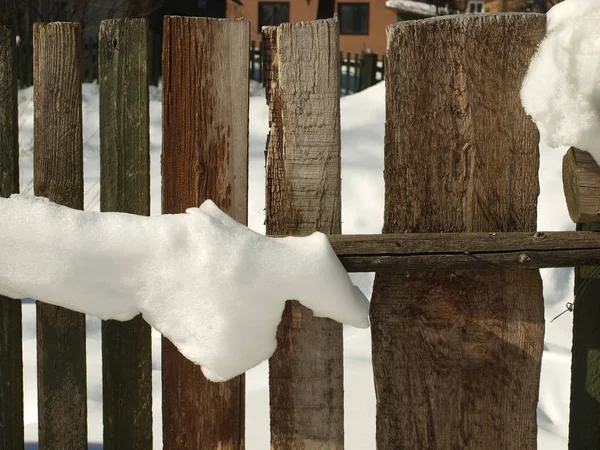 Old wooden village fence covered with snow. Snowy winter in the Royalty Free Stock Images