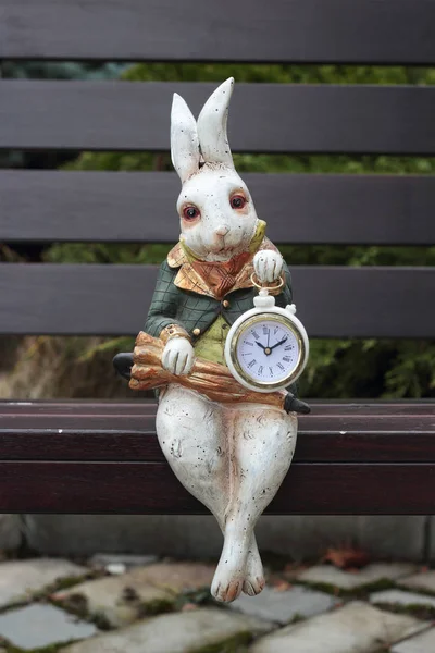 Clock - Hare with umbrella sits on a wooden chair — Stock Photo, Image