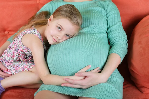 Девушка обнимает живот беременной матери — стоковое фото
