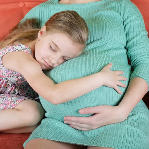 Menina abraçando barriga da mãe grávida — Fotografia de Stock