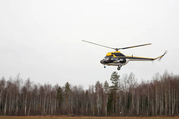 Aereo - elicottero nero-giallo rende il volo a bassa altezza laterale — Foto Stock