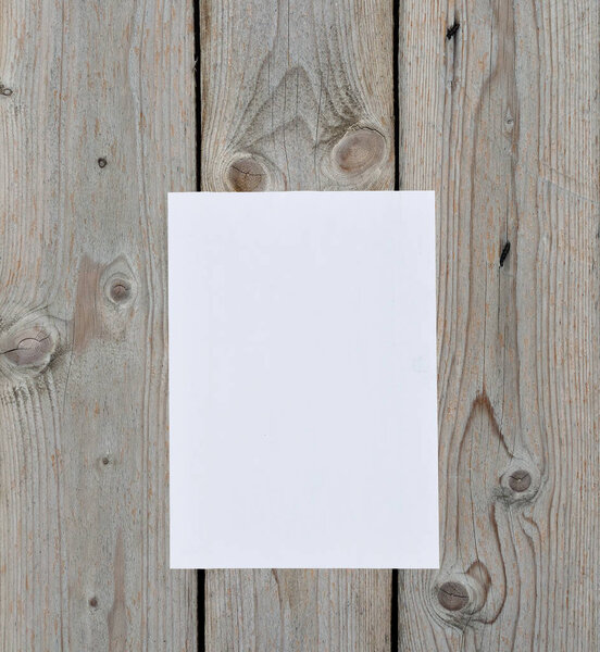 A sheet of pure white paper is vertically glued to the wall of old wooden boards