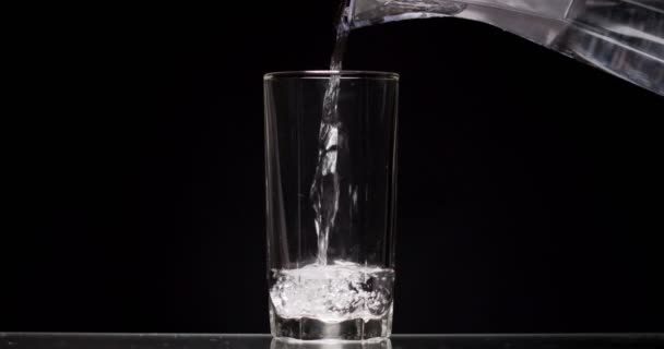 homme verse un verre d'eau sur un fond noir 