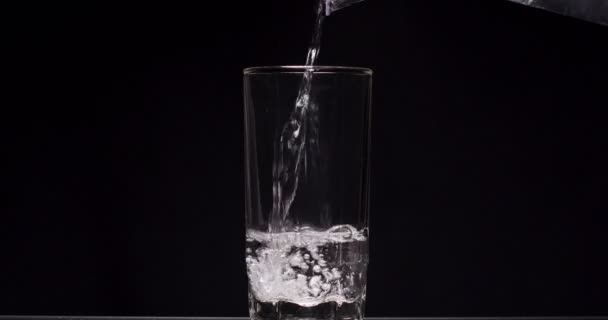 Muž nalévá sklenici vody na černé pozadí — Stock video