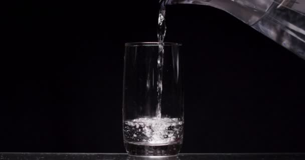 Man pours a glass of water on a black background — ストック動画