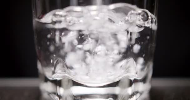 Человек наливает стакан воды на черный фон — стоковое видео