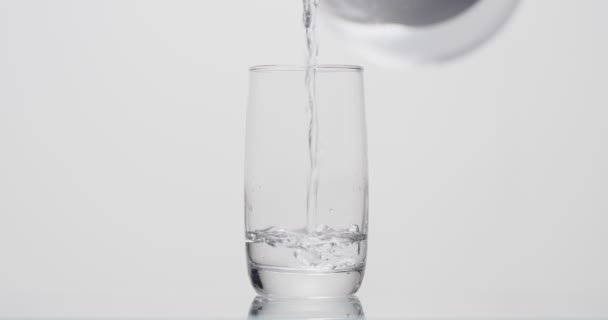Человек наливает стакан воды на белом фоне — стоковое видео