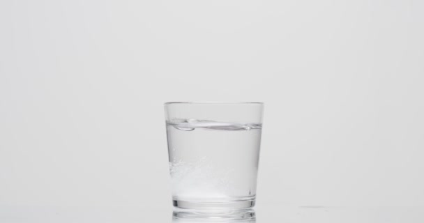 patient jette de l'aspirine dans un verre d'eau sur fond blanc 