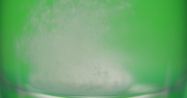 Paciente arroja aspirina en un vaso de agua sobre un fondo verde — Vídeo de stock